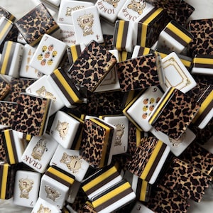 May include: A collection of rectangular mahjong tiles featuring a mix of designs, including leopard print patterns, yellow and black striped edges, and white tiles with illustrations of ladybugs, tigers, and the text Joker, Crak, and Ba.