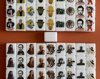 May include: A set of 48 white dominoes with various images printed on them. The images include characters from the TV shows Breaking Bad and Game of Thrones. The dominoes are arranged in a grid pattern on a brown surface.