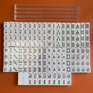 May include: A set of 144 white mahjong tiles with black and red markings. The tiles are arranged in rows and columns, with the numbers 1 through 9, the characters 'East', 'South', 'West', 'North', and 'Wind', and the words 'Spring', 'Summer', 'Autumn', and 'Winter'. There are also four joker tiles.