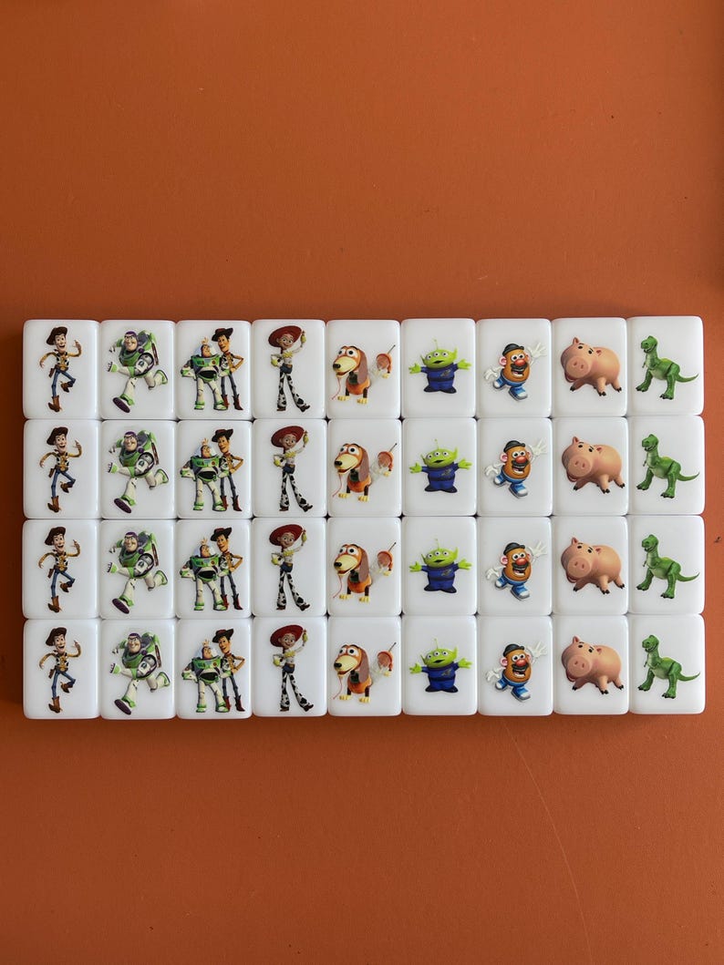 May include: A collection of white rectangular tiles featuring colorful images of characters from the animated film "Toy Story." The tiles display characters like Woody, Buzz Lightyear, and others, arranged in rows.