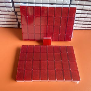 May include: Two sets of red mahjong tiles, each set containing 36 tiles. The tiles are arranged in a rectangular shape and are wrapped in clear plastic.