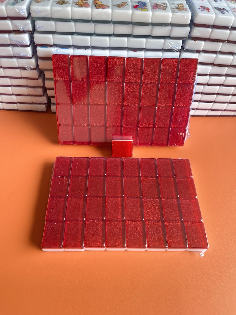 May include: Two sets of red mahjong tiles, each set containing 36 tiles. The tiles are arranged in a rectangular shape and are wrapped in clear plastic.
