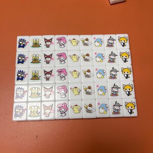 Pu&ograve; includere: Un set di 36 tessere di mahjong bianche con personaggi dei cartoni animati colorati su ogni tessera. I personaggi includono un gatto nero, un pulcino giallo, un coniglio rosa, un cane bianco, un pinguino blu e una volpe rossa.