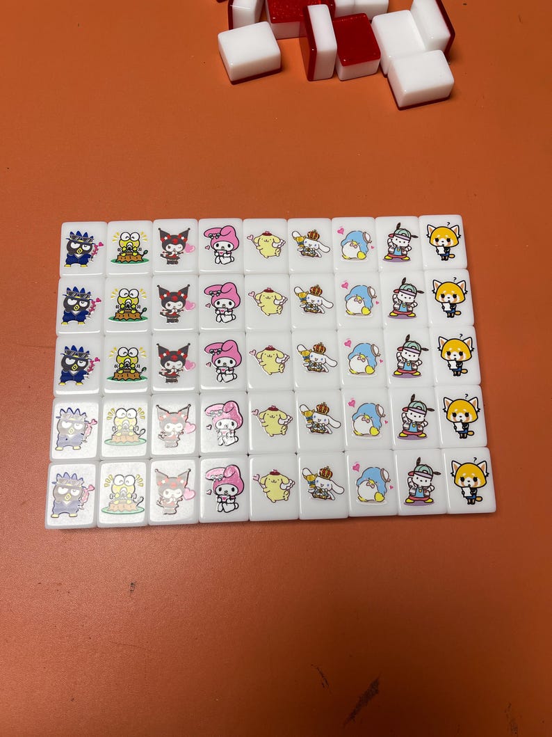 Pu&ograve; includere: Un set di 36 tessere di mahjong bianche con personaggi dei cartoni animati colorati su ogni tessera. I personaggi includono un gatto nero, un pulcino giallo, un coniglio rosa, un cane bianco, un pinguino blu e una volpe rossa.