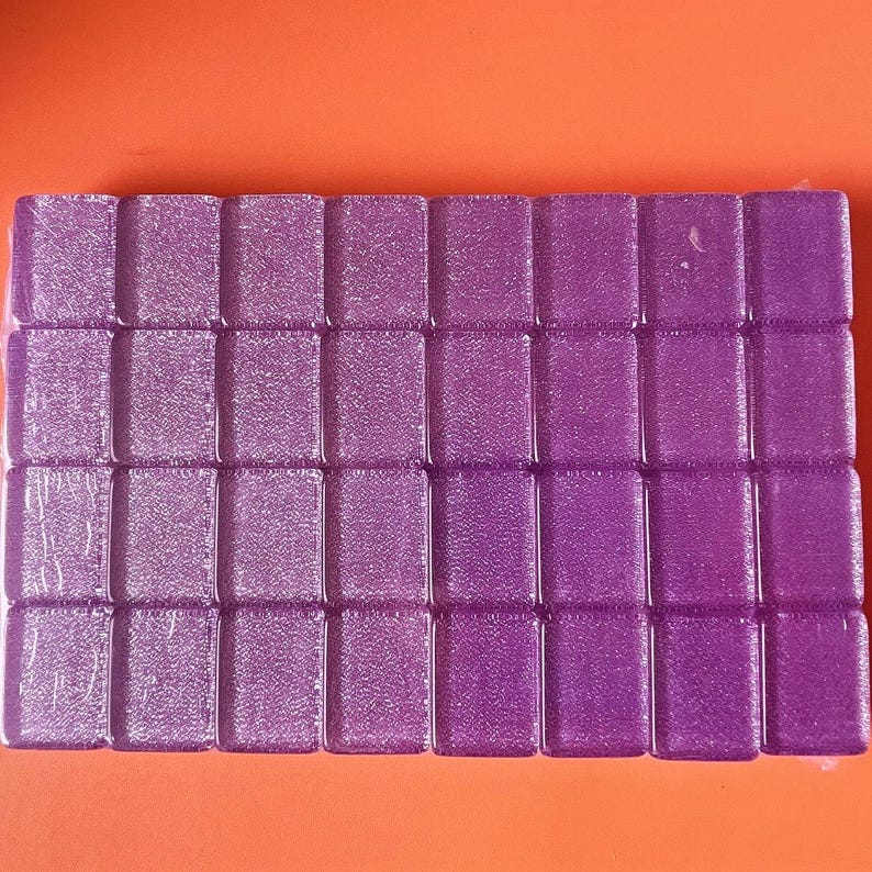 May include: A rectangular arrangement of small, purple, textured tiles. The tiles are evenly spaced and appear to be made of a translucent material. The background is a solid orange color.
