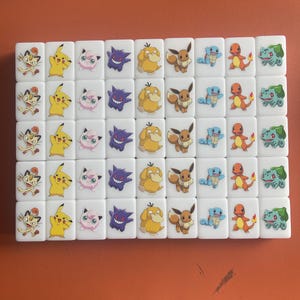 Pu&ograve; includere: Un set di 48 domino bianchi con personaggi Pokemon colorati stampati su ogni tessera. I personaggi includono Pikachu, Eevee, Squirtle, Charmander, Bulbasaur e molti altri.