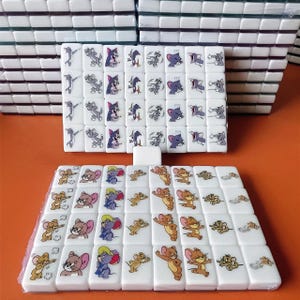 May include: A set of white dominoes with cartoon images of Tom and Jerry. The dominoes are arranged in a grid pattern with the Tom and Jerry images on each domino.