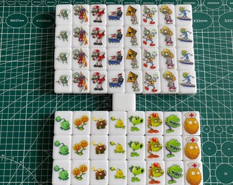 May include: A set of 38 white dominoes with colorful images of plants and zombies from the popular video game Plants vs. Zombies. The dominoes are arranged in a grid pattern on a green grid surface. The dominoes are approximately 3.8 cm wide and 2.8 cm tall.