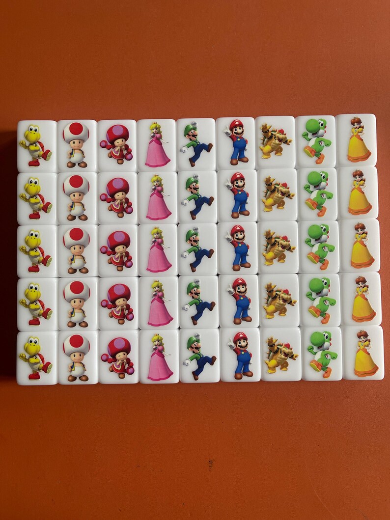 May include: A set of 40 white square tiles with different Mario characters printed on them. The characters include Mario, Luigi, Peach, Toad, Bowser, and Yoshi.
