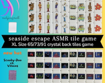 Peut inclure: Un ensemble de tuiles en céramique blanche avec des images de Scooby-Doo et de la Mystery Machine. Les tuiles font partie d'un "jeu de tuiles ASMR d'évasion en bord de mer" et sont de taille XL 65/73/91. Les tuiles sont disposées en grille et ont un dos en cristal.
