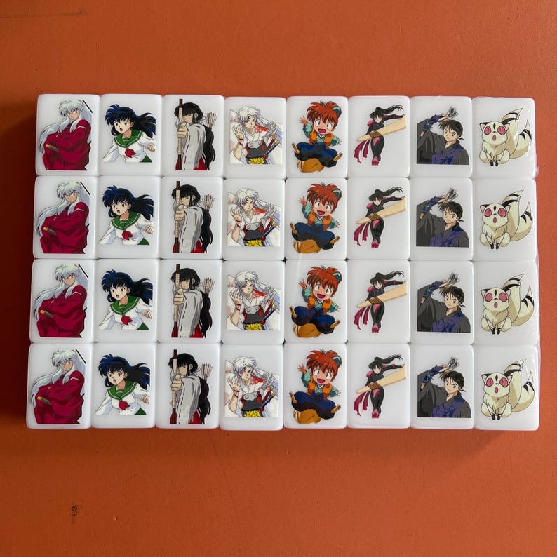 May include: A set of white Mahjong tiles featuring colorful anime character illustrations. Each tile displays a different character, with a variety of poses and outfits. The tiles are arranged in neat rows and columns, creating a visually appealing pattern.