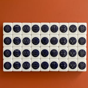 May include: A set of 40 white dominoes with a blue background and gold zodiac symbols. Each domino features a different zodiac sign.