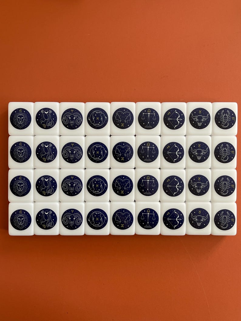 May include: A set of 40 white dominoes with a blue background and gold zodiac symbols. Each domino features a different zodiac sign.