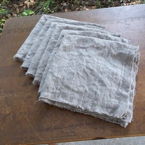 May include: A stack of six gray linen napkins with frayed edges.