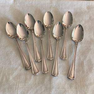 May include: Eight silver teaspoons with a simple design. Each spoon has a small engraved letter 'W' on the handle.