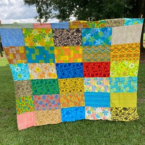 May include: A patchwork quilt with a variety of colorful floral patterns. The quilt is made up of 16 squares, each with a different design. The quilt is made of a variety of fabrics, including cotton and linen.