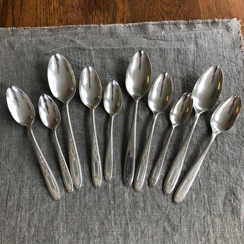 Ten silver plate spoons in the Grovesnor pattern.  Spoons have ornate designs on handles.