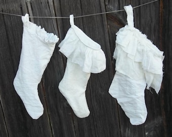 May include: Three white stockings with ruffles hanging on a wooden fence. The stockings are made of a soft, white fabric and have a delicate, feminine look.