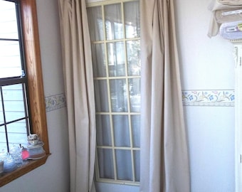 May include: A pair of off-white linen curtains with ruffles at the bottom hang on a white rod in front of a glass door. The curtains are long enough to reach the floor.