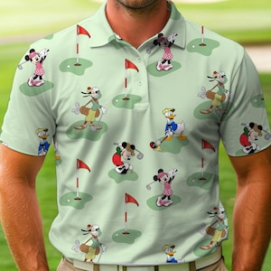 May include: Light green polo shirt featuring a repeating pattern of cartoon characters playing golf. The design includes Mickey Mouse, Minnie Mouse, Donald Duck, and Goofy, along with golf flags and putting greens. The shirt has a collared neckline and button closure.