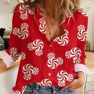May include: Red button-down shirt with a white and red peppermint candy pattern. The long-sleeved shirt has white cuffs and is made of a lightweight fabric. The shirt is unbuttoned at the top.