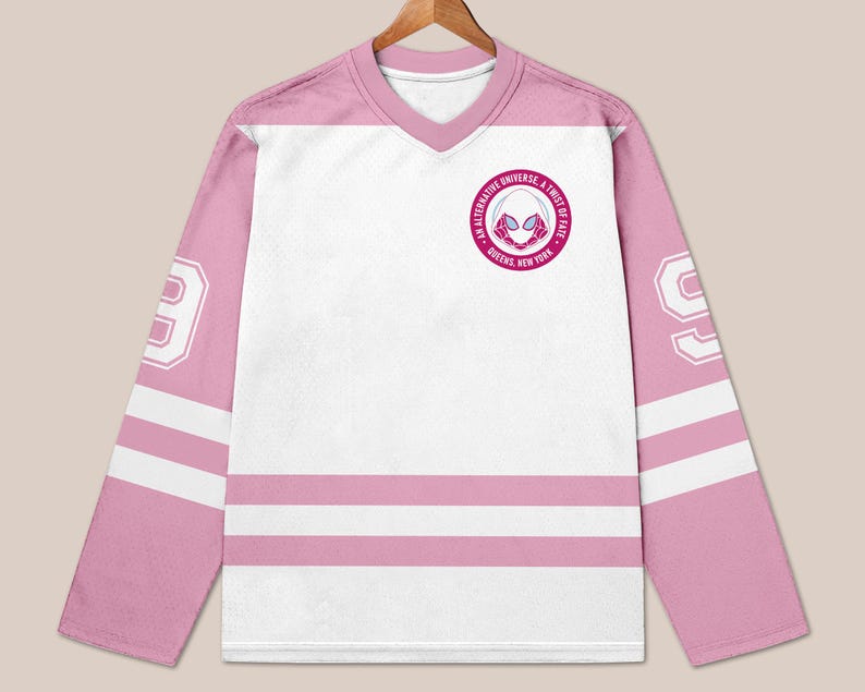 May include: A white and pink hockey jersey with long sleeves. The jersey features a V-neck collar and the number 99 on the sleeves. A circular emblem with text and a spider-themed graphic is on the chest.