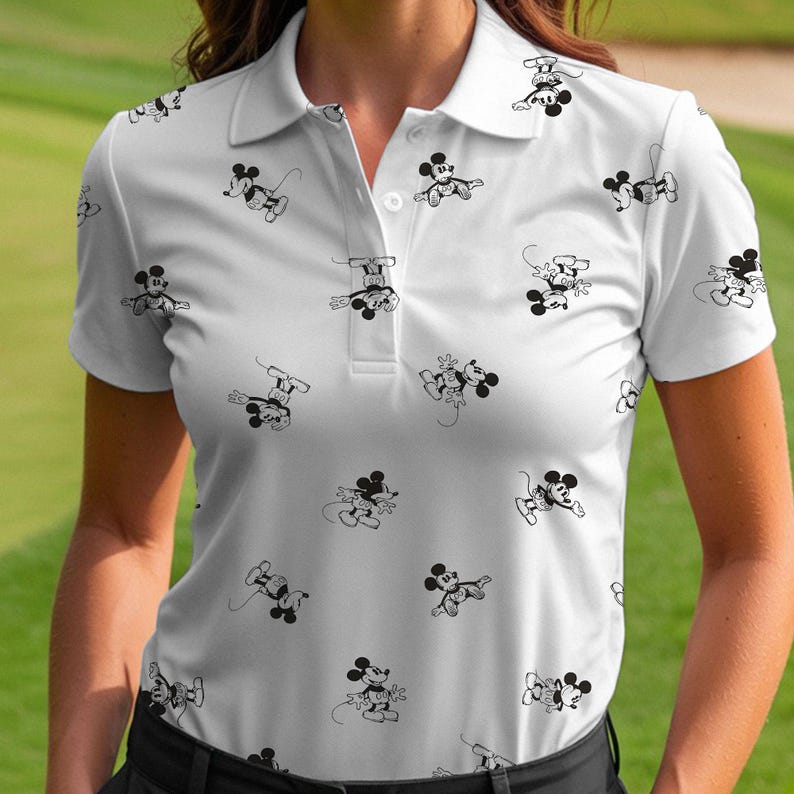 Puede incluir: Polo blanco con un patr&oacute;n repetido de ilustraciones de Mickey Mouse en blanco y negro. La camisa tiene cuello, mangas cortas y tapeta abotonada. El dise&ntilde;o es una versi&oacute;n l&uacute;dica y caprichosa de un polo cl&aacute;sico.