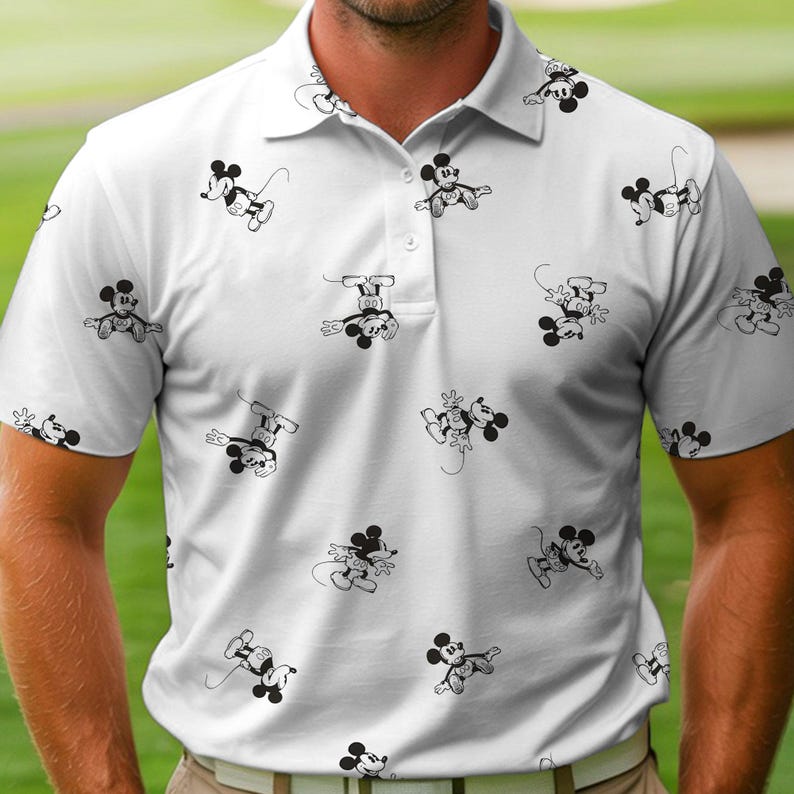 Puede incluir: Polo blanco con un estampado repetido de ilustraciones de Mickey Mouse en blanco y negro. La camisa tiene un cuello cl&aacute;sico, mangas cortas y una tapeta de tres botones. El dise&ntilde;o es informal y adecuado para diversas ocasiones.