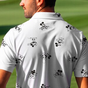Puede incluir: Polo blanco con un patr&oacute;n repetido de ilustraciones de Mickey Mouse en blanco y negro. La camisa tiene mangas cortas y cuello. Un dise&ntilde;o divertido en un polo cl&aacute;sico.