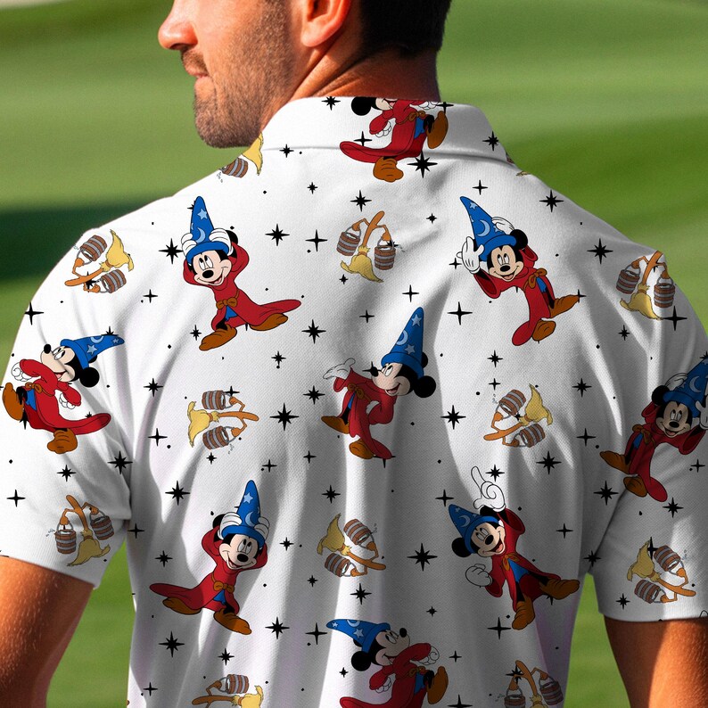 Puede incluir: Polo blanco con un estampado repetido de Mickey Mouse con un disfraz de mago, estrellas y otros elementos de dibujos animados. La camisa tiene mangas cortas y un cuello cl&aacute;sico. El dise&ntilde;o incluye colores rojo, azul y amarillo.