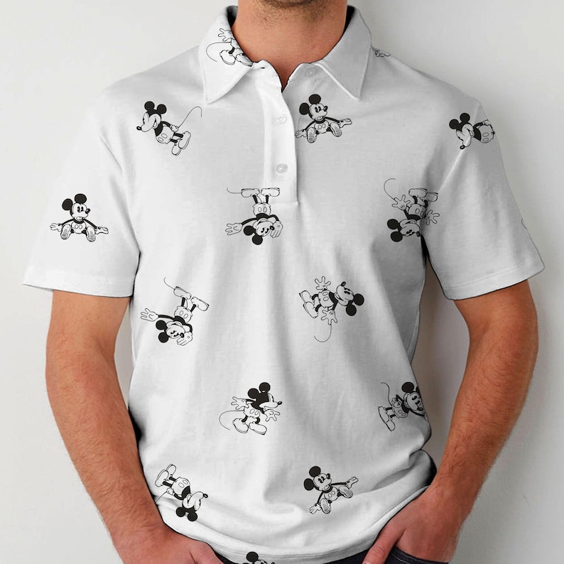 Puede incluir: Polo blanco con un patr&oacute;n repetido de ilustraciones de Mickey Mouse en blanco y negro. La camisa de manga corta tiene cuello y tapeta abotonada.
