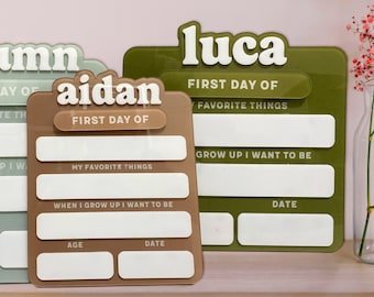 May include: Three colorful first day of school boards. The boards are in shades of green, brown, and blue-green. Each board has a name at the top, with sections for "My Favorite Things," "When I Grow Up I Want to Be," and "Date."
