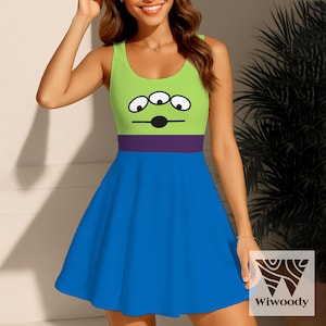 May include: A sleeveless dress featuring a cartoon alien design. The top is lime green with three eyes and a black mouth, separated by a purple band from the blue skirt. The dress has a scoop neckline and a flared skirt.