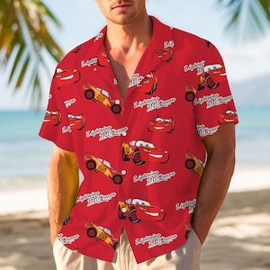 May include: Red button-down shirt featuring a repeating pattern of Lightning McQueen from the Cars movie. The design includes images of the character and the text "Lightning McQueen" and "95". The shirt has short sleeves and a classic collar.