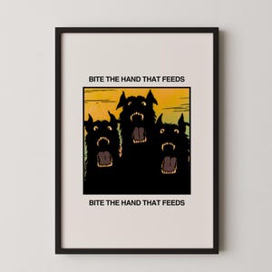 May include: Framed art print featuring three snarling black dogs with open mouths against a yellow and green background. The text "BITE THE HAND THAT FEEDS" is printed above and below the image in black font.