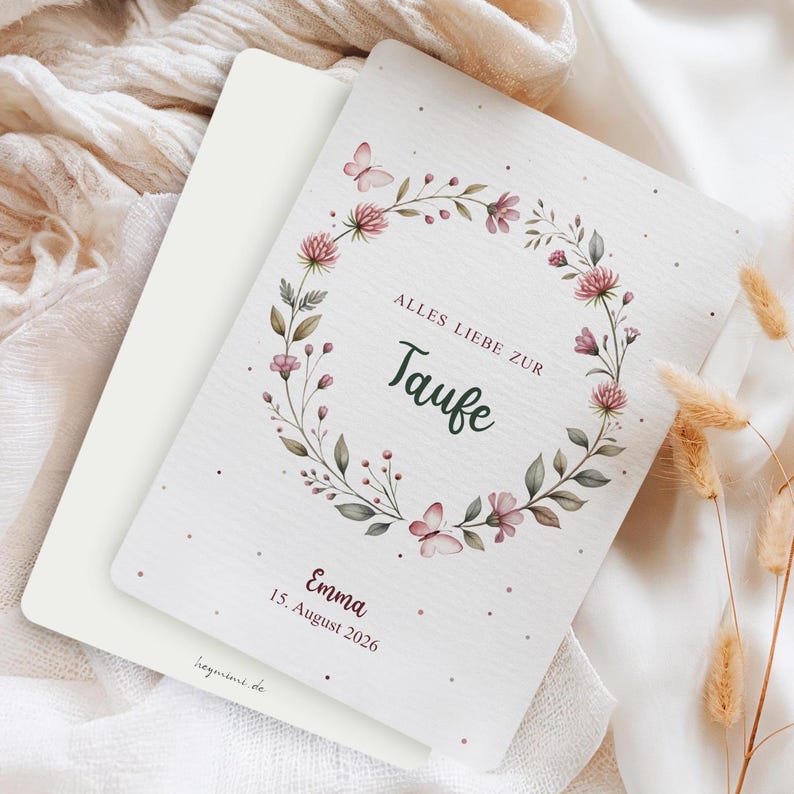 Puede incluir: Tarjeta blanca con un dise&ntilde;o de corona floral, con flores rosas y mariposas, con el texto "Alles Liebe zur Taufe", el nombre "Emma" y la fecha "15. August 2026". La tarjeta es parte de un conjunto.