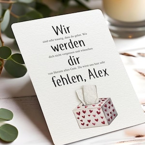 Könnte beinhalten: Eine weiße Karte mit deutschem Text, darunter "Wir werden dir fehlen, Alex." Die Karte zeigt eine kleine Aquarellillustration einer Taschentuchbox mit roten Herzen. Im Hintergrund sind Grün und eine Kerze zu sehen.