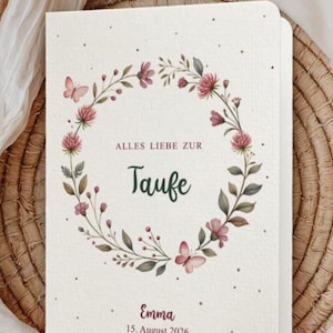 Puede incluir: Una invitaci&oacute;n color crema con un dise&ntilde;o de corona floral. La corona presenta flores rosas, hojas verdes y mariposas. El texto dice "Alles Liebe zur Taufe" y "Emma, 15 de agosto de 2026".