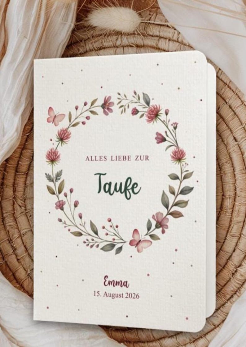 Puede incluir: Una invitaci&oacute;n color crema con un dise&ntilde;o de corona floral. La corona presenta flores rosas, hojas verdes y mariposas. El texto dice "Alles Liebe zur Taufe" y "Emma, 15 de agosto de 2026".