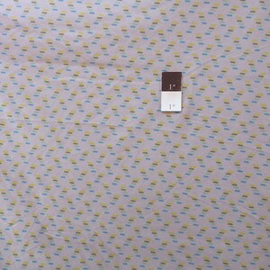 May include: A close-up of a light pink fabric with a repeating pattern of small, diagonal lines in yellow, blue, and green. A brown ruler with the text "1" is visible in the image.