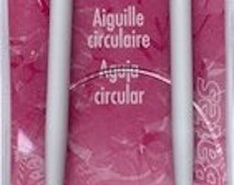 Può includere: Un paio di ferri da maglia circolari bianchi con un'etichetta rosa e bianca che recita "Susan Bates Circular Knitting Needle". L'etichetta include anche il testo "Aiguille circulaire" e "Aguja circular".
