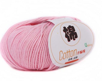 May include: A pink ball of cotton yarn with a white label that says "Cotton" in English and Chinese characters. The label also has the word "Umissy" on it.