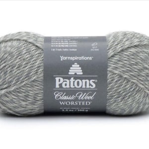 Könnte beinhalten: Eine Knäuel Patons Classic Wool Worsted Garn in einem grau-weißen Melange-Farbton. Das Etikett lautet "Patons Classic Wool Worsted" und "Yarnspirations".