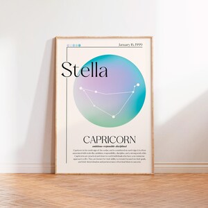 May include: A framed poster with a Capricorn zodiac design. The poster has a light beige background with the name "Stella" in large black text. A colourful blue, purple, and green circle contains the Capricorn constellation.
