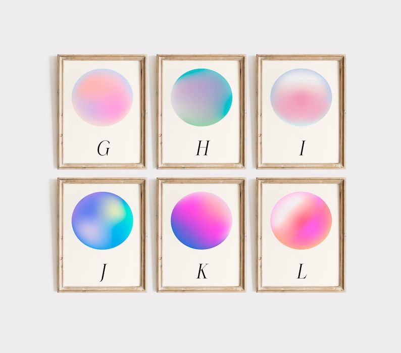 May include: Six framed art prints with a minimalist design. Each print features a gradient sphere in shades of pink, blue, and purple. The letters G, H, I, J, K, and L are printed below each sphere. The frames are a light brown colour.
