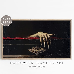 May include: A framed Halloween-themed artwork depicts a skeletal hand with long, sharp claws emerging from a dark, ornate box. The hand is reaching out over a red fabric. The artwork is labeled "Halloween Frame TV Art".