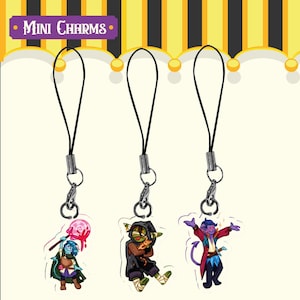 Puede incluir: Tres mini colgantes con cordones negros y cierres plateados. Cada colgante presenta un diseño de personaje de dibujos animados colorido. La parte superior de la imagen tiene el texto "Mini Charms" en blanco sobre una pancarta morada.