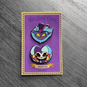 Peut inclure: Deux &eacute;pingles en &eacute;mail sur une carte violette. L'&eacute;pingle sup&eacute;rieure est un personnage de dessin anim&eacute; bleu et violet avec un chapeau. L'&eacute;pingle inf&eacute;rieure est un personnage en forme de c&oelig;ur avec un visage. La carte indique "HELLUVA CUTE" et "&eacute;pingle en &eacute;mail".