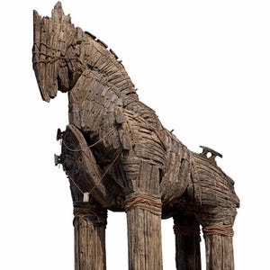 May include: A large, weathered wooden sculpture of the Trojan Horse. The horse is constructed from wooden planks and beams, with rope binding the legs. The sculpture stands on a rectangular wooden base, showcasing a historical theme.