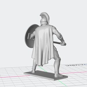 K&ouml;nnte beinhalten: Graue 3D-gedruckte Figur eines spartanischen Kriegers, von hinten gesehen. Der Krieger tr&auml;gt eine R&uuml;stung, einschlie&szlig;lich Helm, Umhang und Beinschienen, und h&auml;lt einen Schild und einen Speer. Die Figur steht auf einem rechteckigen Sockel.
